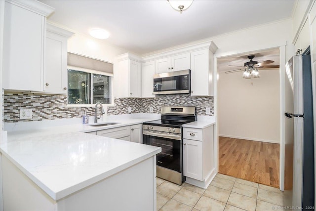 kitchen featuring white cabinetry, sink, decorative backsplash, kitchen peninsula, and stainless steel appliances