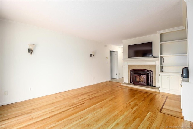 unfurnished living room featuring a tiled fireplace, crown molding, and hardwood / wood-style floors