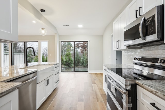 kitchen with appliances with stainless steel finishes, white cabinetry, and light stone counters