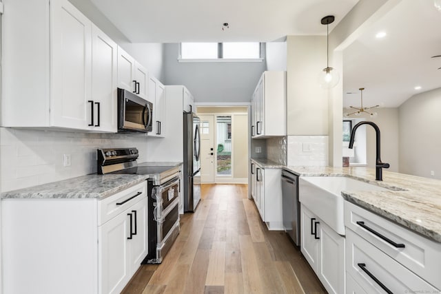 kitchen with white cabinets, pendant lighting, stainless steel appliances, and a wealth of natural light