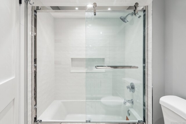 bathroom with shower / bath combination with glass door and toilet