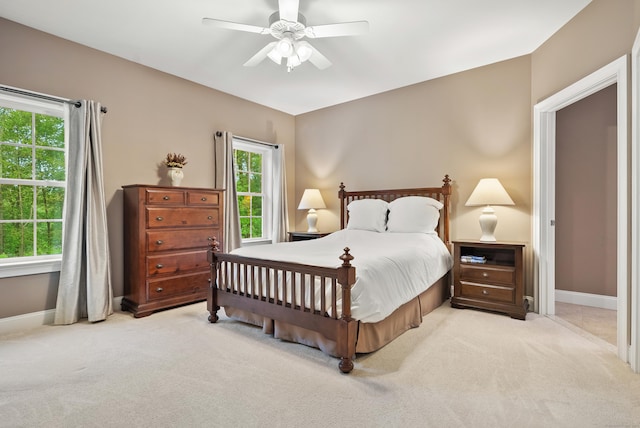 bedroom featuring light colored carpet, baseboards, and ceiling fan