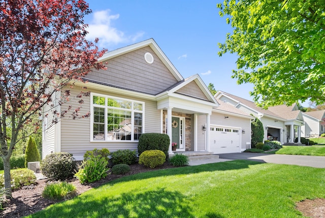 view of front facade with driveway, a front yard, an attached garage, and stone siding