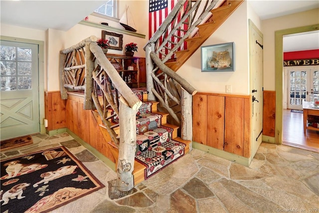 stairway featuring french doors and wooden walls