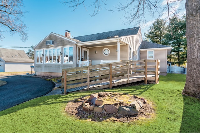 back of house featuring an AC wall unit, a wooden deck, and a yard