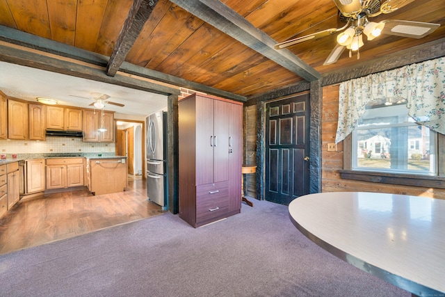 kitchen featuring light brown cabinets, carpet flooring, decorative backsplash, beam ceiling, and stainless steel refrigerator