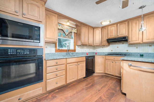 kitchen featuring sink, light stone counters, hanging light fixtures, and black appliances