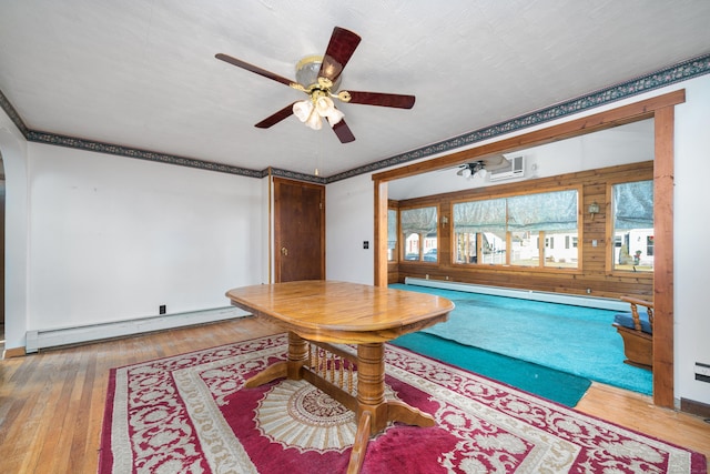 interior space with wood-type flooring, baseboard heating, crown molding, and ceiling fan