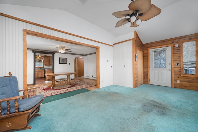 carpeted living room featuring ceiling fan, wooden walls, and vaulted ceiling