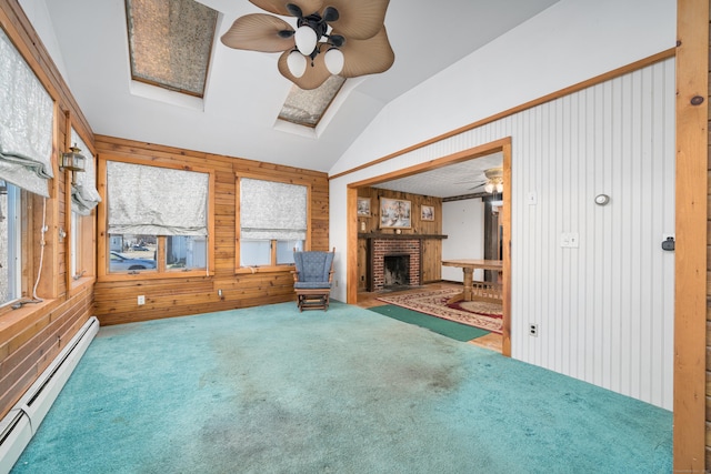 interior space with baseboard heating, lofted ceiling with skylight, wood walls, carpet floors, and a fireplace