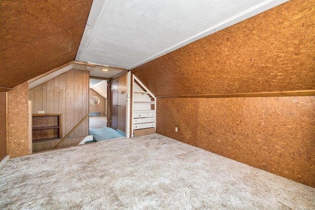 bonus room featuring carpet, lofted ceiling, and wooden walls