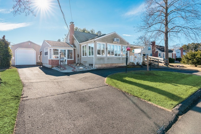 ranch-style home with an outbuilding, a sunroom, a garage, and a front yard