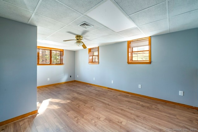 basement featuring a paneled ceiling, ceiling fan, and light wood-type flooring