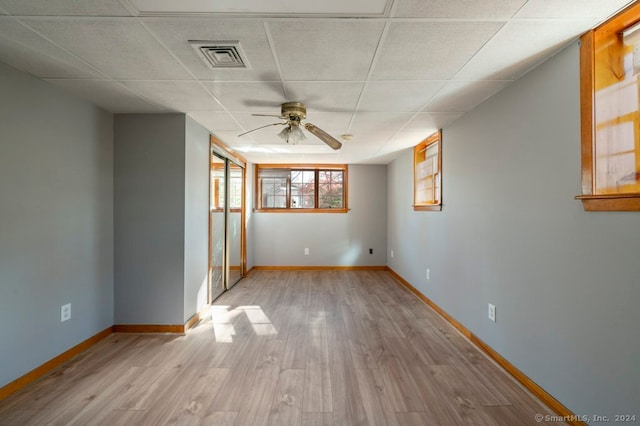 spare room with ceiling fan, light hardwood / wood-style floors, and a drop ceiling