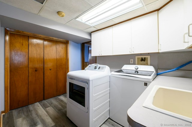 clothes washing area with washer and dryer, sink, cabinets, and wood-type flooring