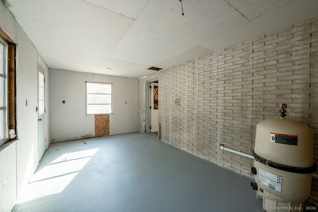 unfurnished room featuring concrete floors and brick wall