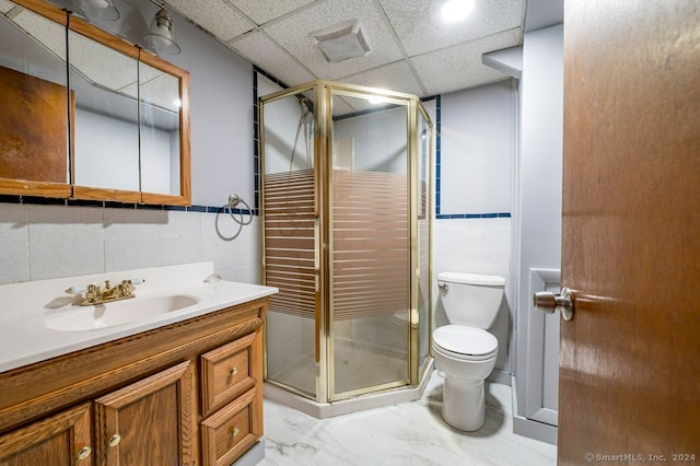 bathroom with a paneled ceiling, an enclosed shower, vanity, tile walls, and toilet