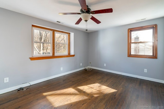 empty room featuring ceiling fan, plenty of natural light, and dark hardwood / wood-style floors