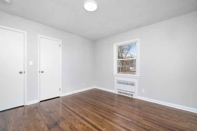 unfurnished room featuring dark wood-type flooring and radiator