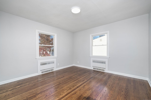 spare room featuring dark hardwood / wood-style floors and radiator