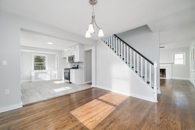 unfurnished living room featuring wood-type flooring and a chandelier