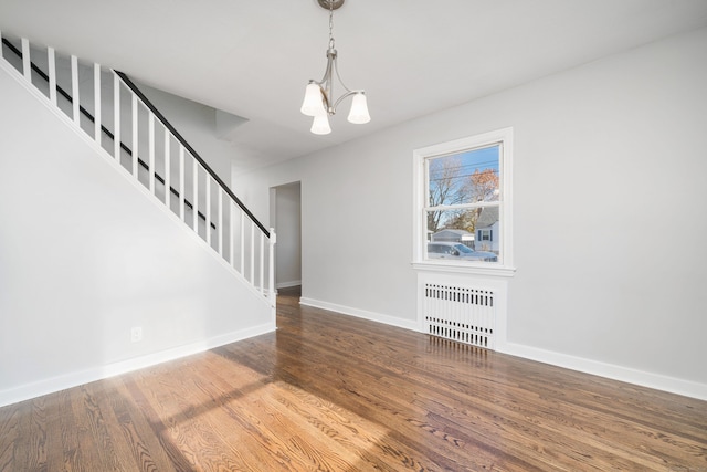 interior space featuring hardwood / wood-style flooring, a notable chandelier, and radiator heating unit