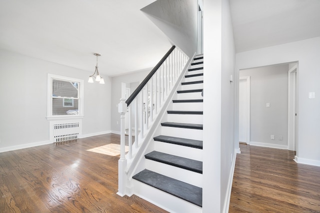 stairway featuring hardwood / wood-style flooring, radiator heating unit, and an inviting chandelier