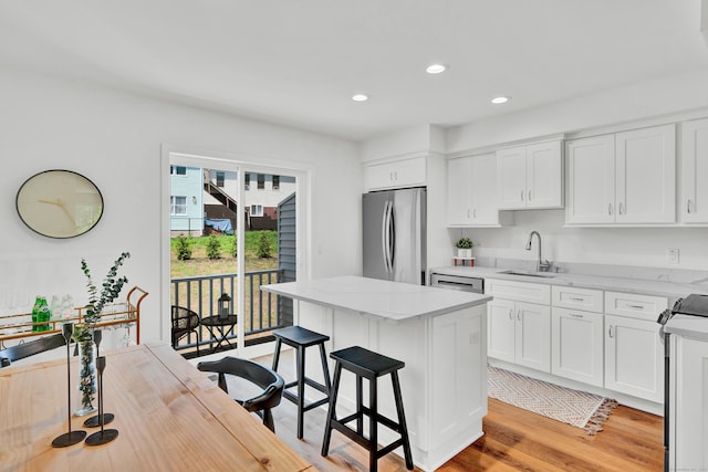 kitchen featuring sink, appliances with stainless steel finishes, white cabinetry, a kitchen breakfast bar, and a kitchen island