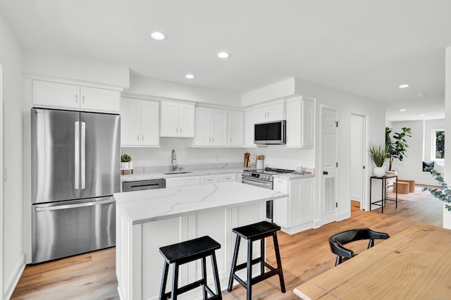 kitchen featuring stainless steel appliances, a kitchen island, and white cabinets