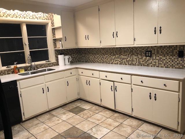 kitchen with dishwasher, tasteful backsplash, light countertops, and a sink