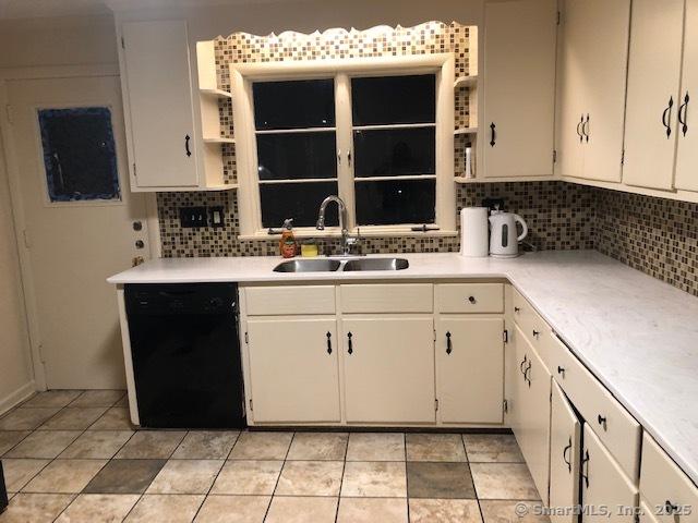 kitchen with light countertops, dishwasher, a sink, and open shelves