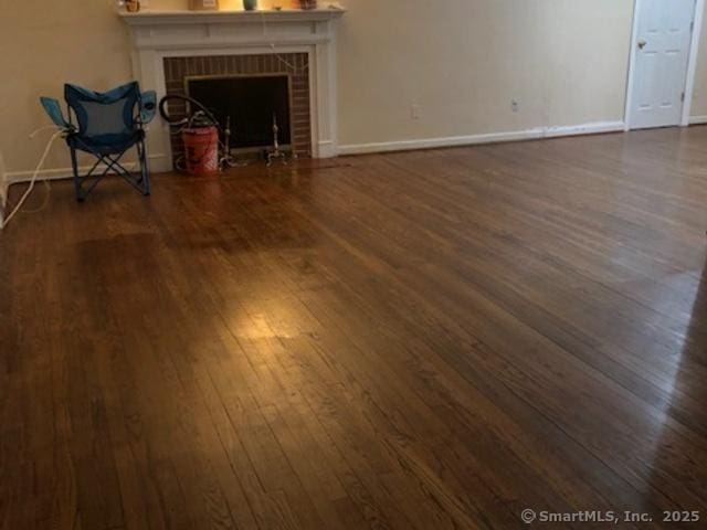 unfurnished living room featuring a fireplace, baseboards, and wood finished floors