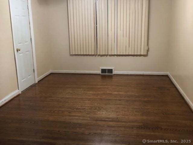 unfurnished room featuring baseboards, visible vents, and dark wood-style flooring