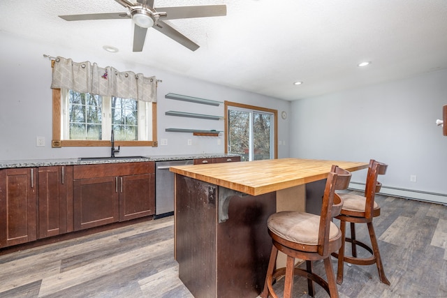 kitchen with butcher block counters, dishwasher, sink, wood-type flooring, and a kitchen island