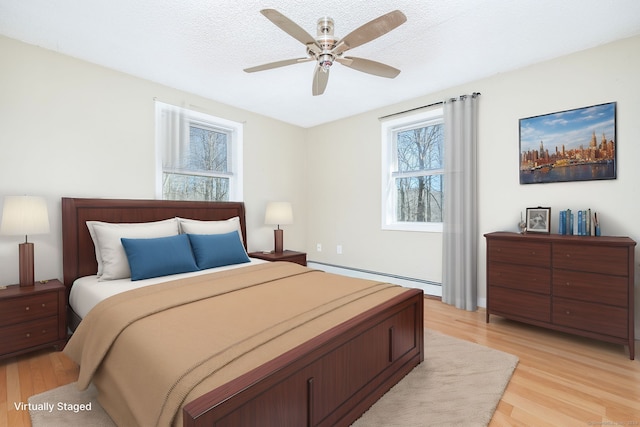 bedroom featuring a textured ceiling, light wood-type flooring, ceiling fan, and a baseboard heating unit