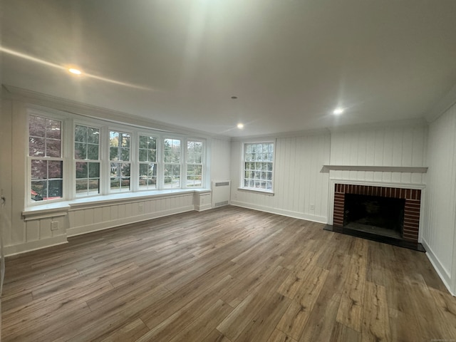 unfurnished living room with hardwood / wood-style flooring, crown molding, and a brick fireplace