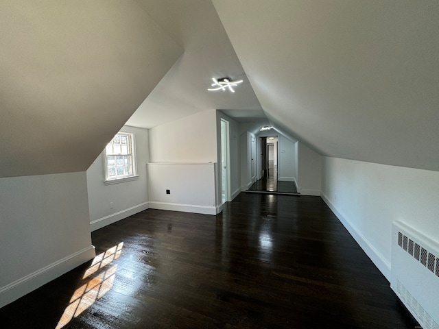 bonus room with dark hardwood / wood-style floors, radiator, and lofted ceiling