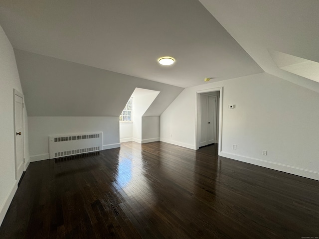 bonus room with lofted ceiling, dark hardwood / wood-style flooring, and radiator heating unit