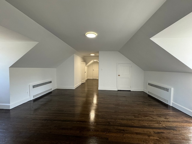 additional living space featuring radiator, lofted ceiling, and dark hardwood / wood-style floors