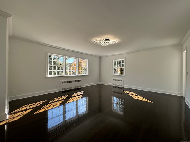 spare room with radiator heating unit, dark hardwood / wood-style floors, and ornamental molding