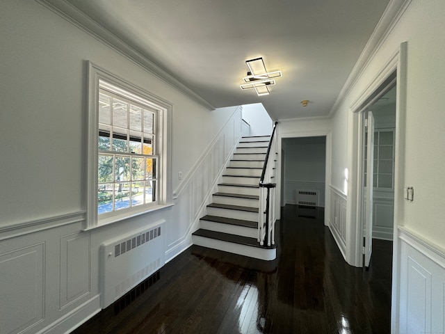 stairway featuring radiator, crown molding, and hardwood / wood-style flooring