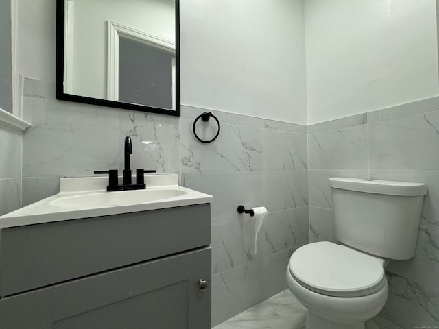 bathroom with vanity, toilet, and tile walls