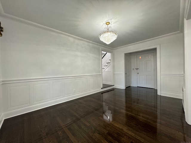 unfurnished dining area featuring dark hardwood / wood-style floors, crown molding, and an inviting chandelier