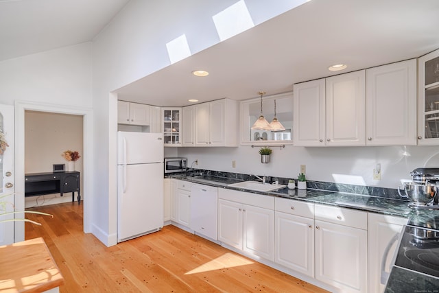 kitchen with pendant lighting, white appliances, white cabinets, sink, and light hardwood / wood-style flooring