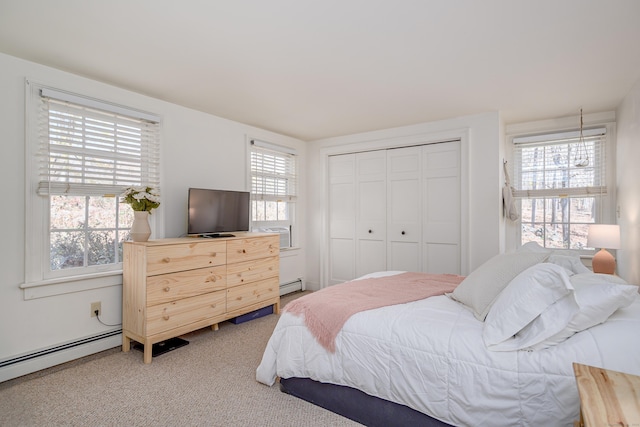 carpeted bedroom with baseboard heating and a closet