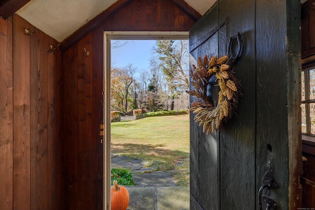 entryway featuring wood walls and lofted ceiling