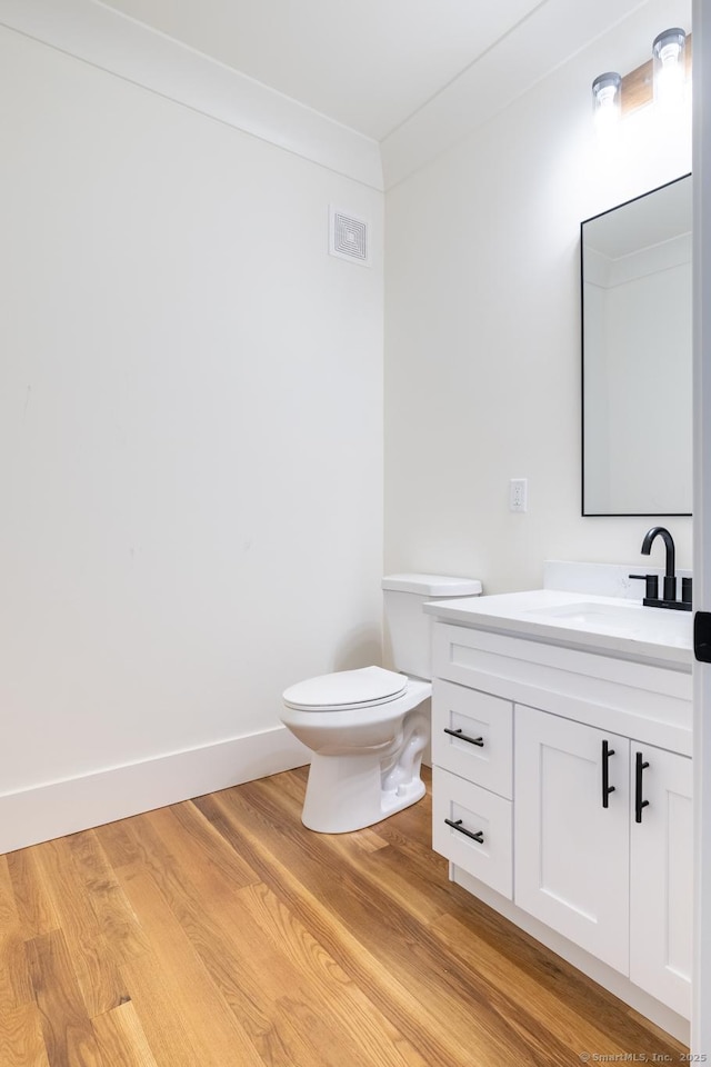 bathroom with hardwood / wood-style flooring, vanity, toilet, and crown molding