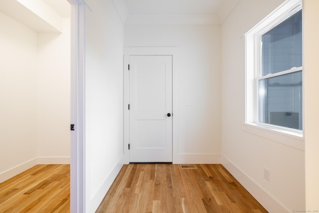 corridor with light hardwood / wood-style floors and crown molding