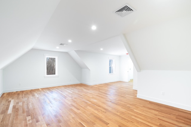 additional living space with light hardwood / wood-style floors, a wealth of natural light, and lofted ceiling