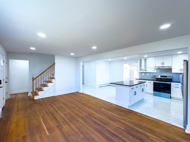 kitchen featuring light wood-type flooring, backsplash, stainless steel appliances, a baseboard heating unit, and white cabinets